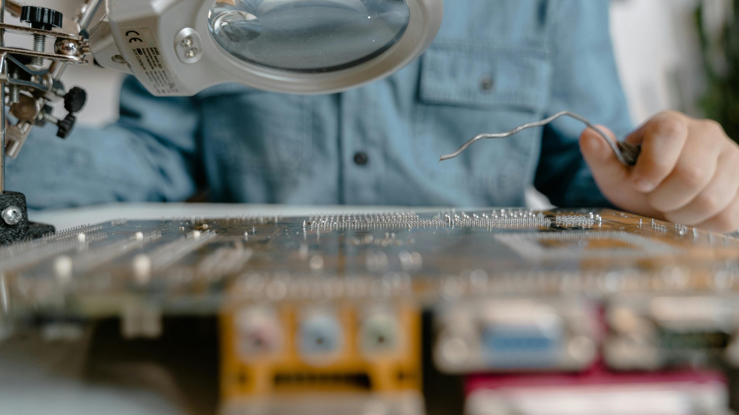 A detailed view of electronic circuit inspection using a magnifying glass and tools.